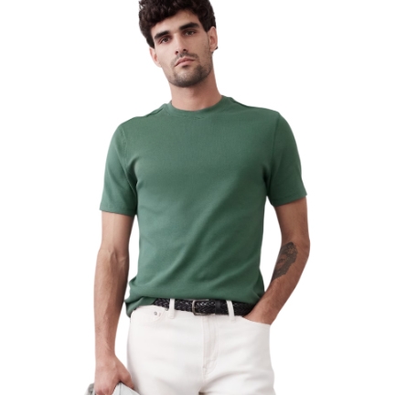 A man is wearing a green ribbed knit tee from Banana Republic, featuring a classic crew neck and short sleeves, paired with light-colored pants and a black belt.