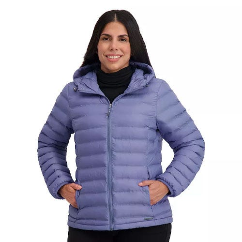 A woman is wearing a light purple puffer jacket with a hood and a front zipper. She has her hands in the jacket's pockets.