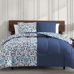 A bedding set with a floral pattern in blue and white tones, including a comforter and pillow shams on a bed.