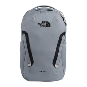 A grey North Face Vault backpack with a front zipper compartment and two side pockets, featuring black adjustable shoulder straps and logo branding.