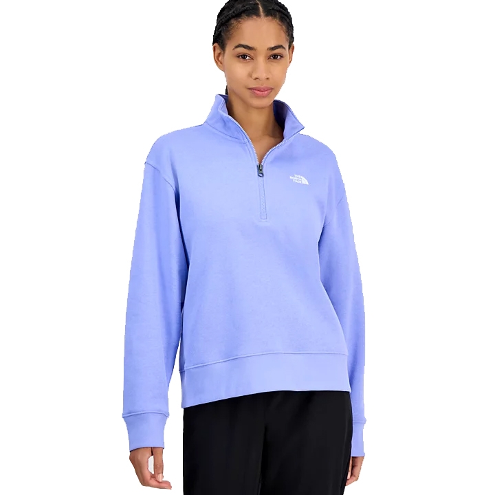 A woman is wearing a light blue The North Face quarter-zip pullover with long sleeves and a relaxed fit, paired with black pants.