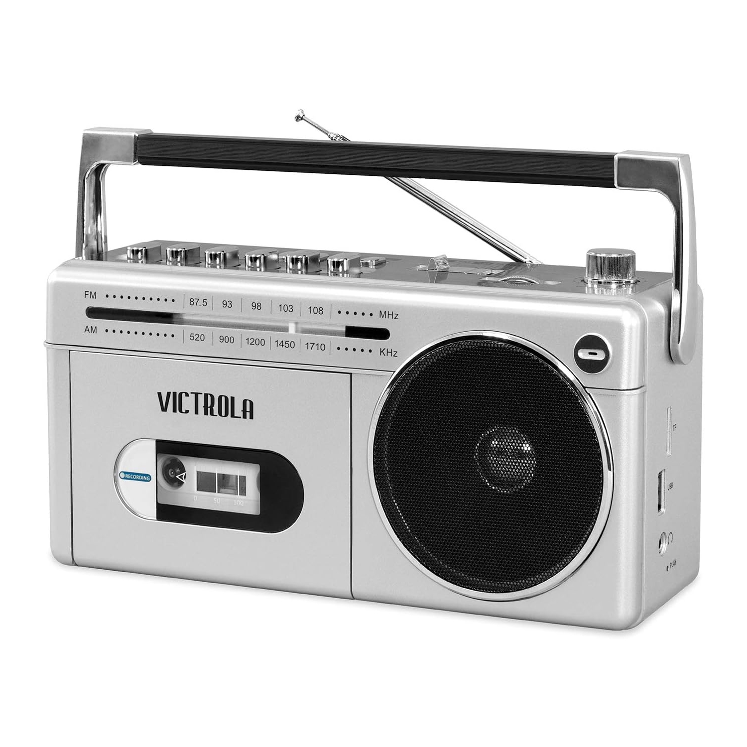 A silver Victrola boombox with a handle, cassette player, and speaker, featuring AM/FM radio and Bluetooth connectivity. The front panel displays frequency settings and a slot for cassette tapes.