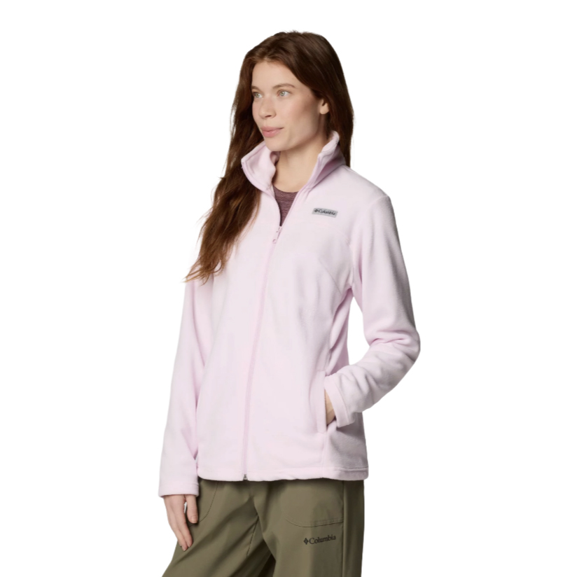 A woman is wearing a light pink Columbia fleece jacket with a full front zipper and collar, paired with olive green pants.