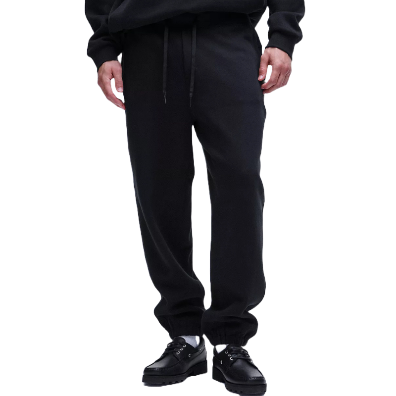 Black sweatpants with a drawstring waistband and elastic cuffs, paired with black lace-up shoes.