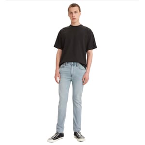 Levi's Men's 510 Skinny Jeans are light blue, close-fitting with a modern, streamlined appearance. They are styled with a black t-shirt and black high-top sneakers.