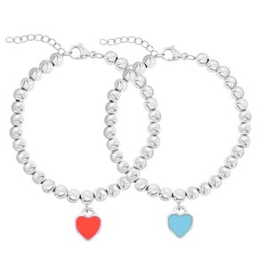 A set of two silver bracelets featuring round beads with heart-shaped charms, one with a red heart and the other with a blue heart. Both bracelets have adjustable chain clasps.