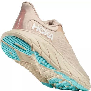 Hoka Arahi 7 Running Shoes feature a beige color with a cushioned, supportive midsole and a breathable upper. The sole has blue accents for traction, designed for stability and comfort.