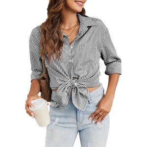 A woman wears a black and white striped button-up shirt tied at the waist, paired with light blue distressed jeans. She carries a brown bag and holds a coffee cup.