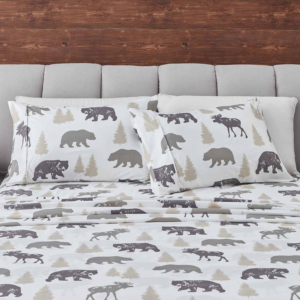 Bedding set featuring a pattern with silhouettes of bears, moose, and trees in neutral tones, against a white background.