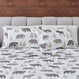 Bedding set featuring a pattern with silhouettes of bears, moose, and trees in neutral tones, against a white background.