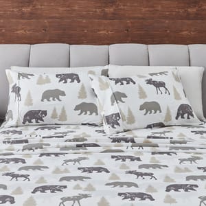 Bedding set featuring a pattern with silhouettes of bears, moose, and trees in neutral tones, against a white background.