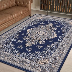 A blue Persian-style rug with intricate floral patterns, placed on a wooden floor, next to a brown tufted leather sofa.