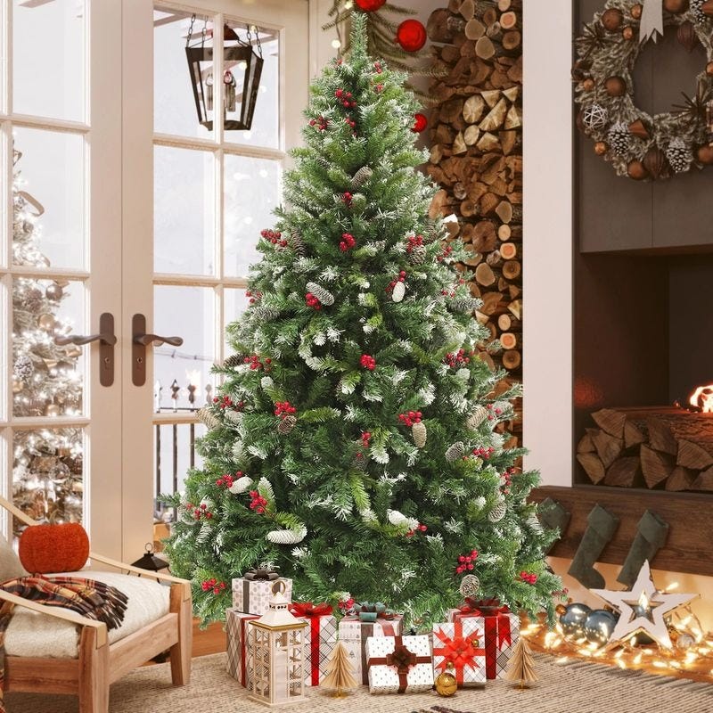 A decorated Christmas tree with red berries, pine cones, and wrapped gifts underneath stands in a cozy room with a fireplace, wood logs, and holiday wreaths.