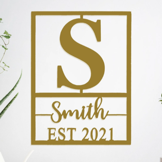 Wall decor featuring a large letter \“S,\“ the name \“Smith,\“ and \“EST 2021,\“ with a minimalist design accompanied by plants on either side.