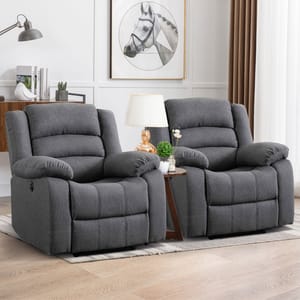 Two gray recliner chairs are placed side by side with a small table in between, featuring a lamp and potted plants.