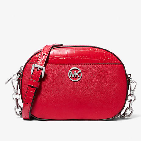 A red crossbody bag with a crocodile pattern, metallic logo on the front, and a chain-and-leather strap.