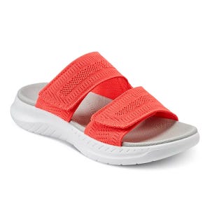 A coral-colored slide sandal with two adjustable mesh straps and a cushioned gray footbed, featuring a white rubber sole designed for comfort.