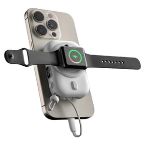 A MagSafe charger power bank attached to the back of a smartphone charges a smartwatch simultaneously, with a visible charging indicator on the smartwatch. The setup is connected via a cable, indicating the power bank's multifunctional charging capability.