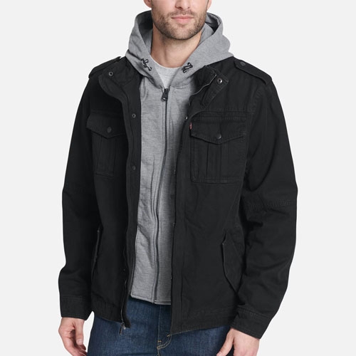 A man wearing a black hooded jacket over a gray hoodie and blue jeans.