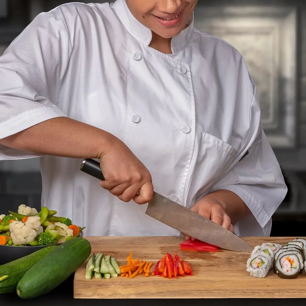 A chef is slicing vegetables on a chopping board with sushi rolls and a bowl of mixed veggies nearby.