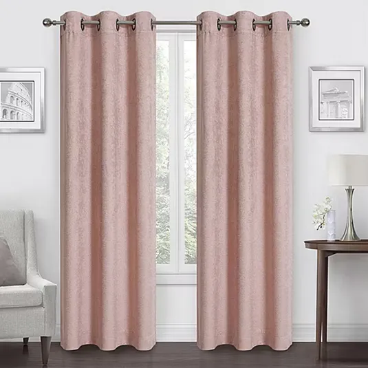 Room with pink curtains on a metal rod, flanked by two framed pictures. A lamp and flowers rest on a side table, with an armchair on the opposite side.