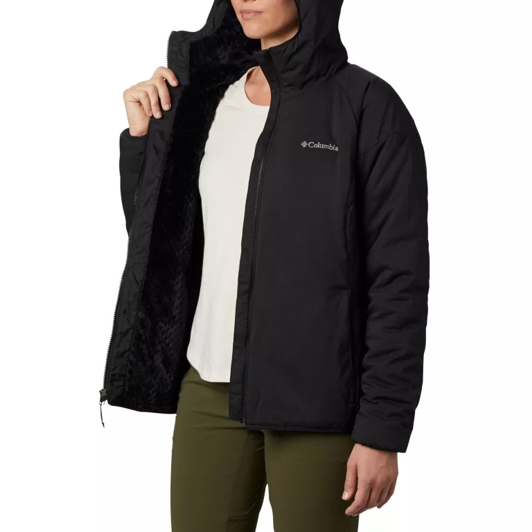A black Columbia hooded jacket with white lining and branding on the chest, paired with green pants.