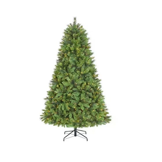 An artificial Christmas tree with a full, lush green appearance, lightly pre-lit with small, evenly distributed white lights, set on a simple black stand.