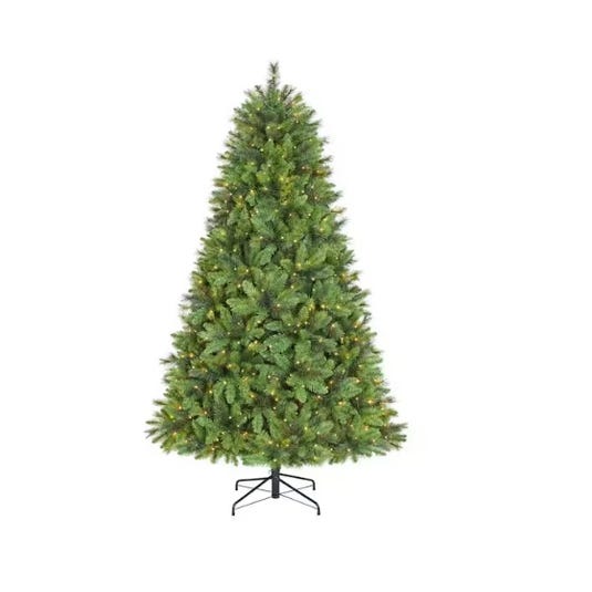 An artificial Christmas tree with a full, lush green appearance, lightly pre-lit with small, evenly distributed white lights, set on a simple black stand.