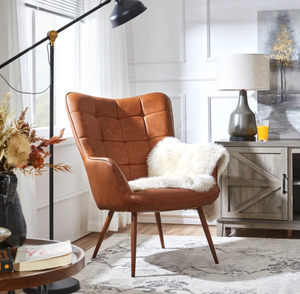 A brown tufted wingback chair with a white fuzzy cushion, beside a wooden sideboard and a floor lamp.