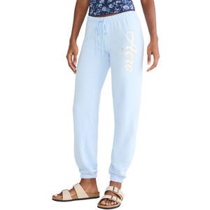 Light blue sweatpants with \“Aero\“ branding on the left leg, paired with a floral top and beige sandals.