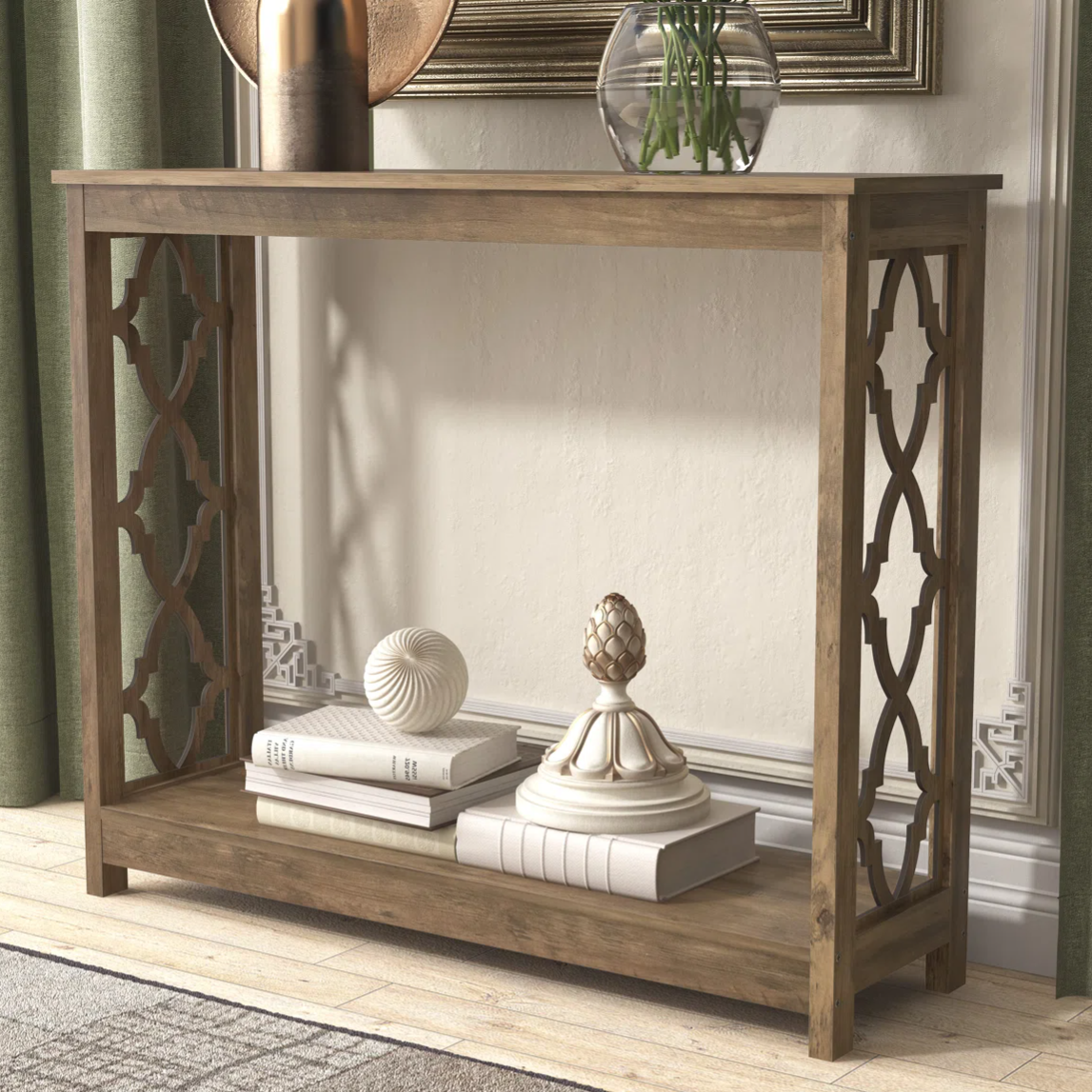 A wooden console table with decorative lattice side panels, featuring several books and decorative objects like a white textured sphere and ornate finial.