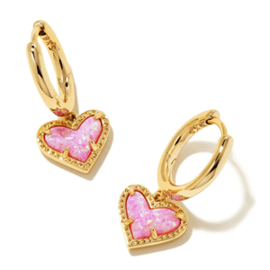 Gold-tone hoop earrings featuring heart-shaped pendants with vibrant pink opal inlay and textured borders, designed by Kendra Scott.