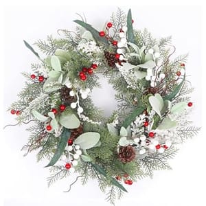 A holiday wreath with green foliage, red berries, white accents, and pine cones against a white background.