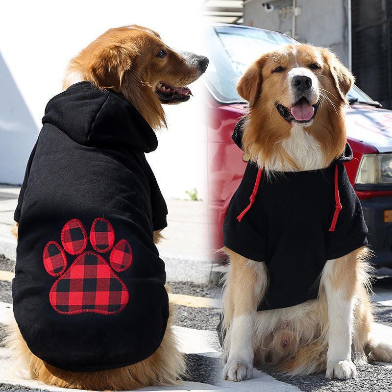 Two golden retrievers wearing black hoodies with red accents; one has a red plaid paw print design on the back.