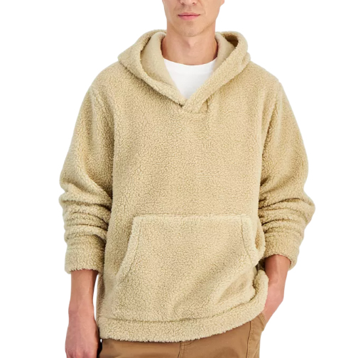 A beige sherpa fleece hoodie with a front pocket and relaxed fit, worn over a white shirt, paired with brown pants.