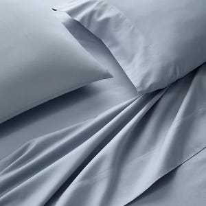 Light blue bed sheets and pillowcases with a smooth texture are displayed, suggesting a soft and comfortable fabric.