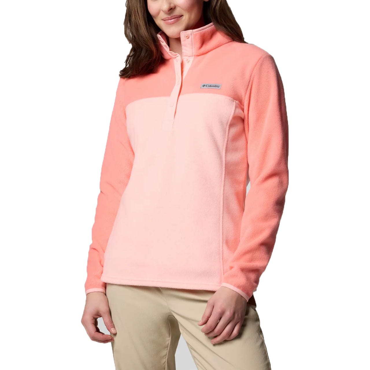 A woman wearing a peach and pink Columbia fleece pullover with a high collar and buttoned placket, paired with light khaki pants.