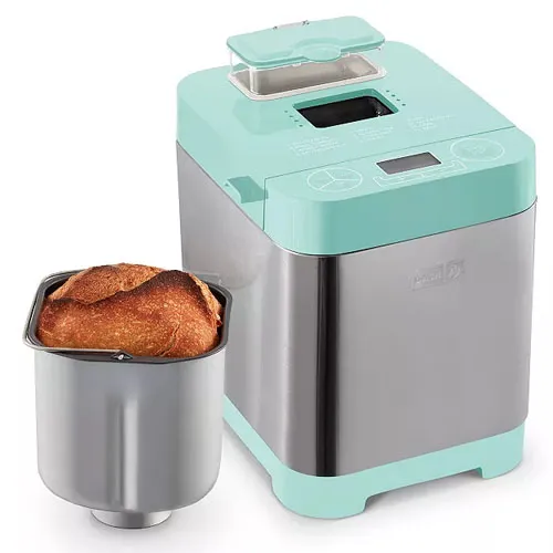 A turquoise bread maker with a stainless steel body next to a freshly baked loaf in a baking pan.
