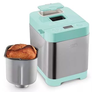 A turquoise bread maker with a stainless steel body next to a freshly baked loaf in a baking pan.