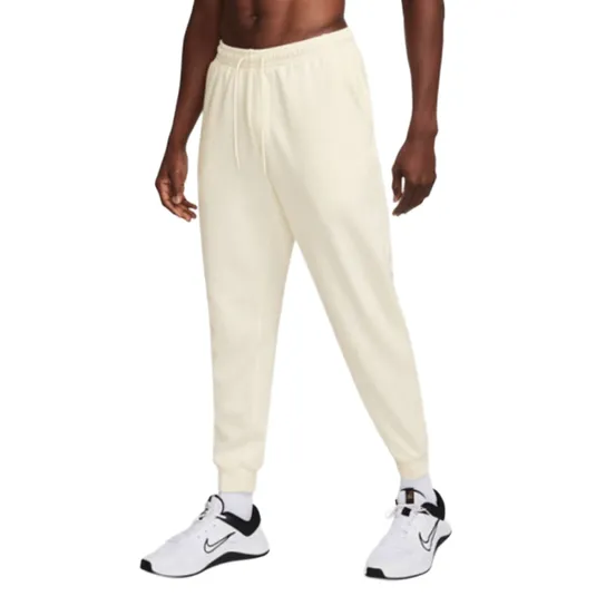 Cream-colored joggers with an elastic waistband and drawstring, paired with white and black Nike sneakers.