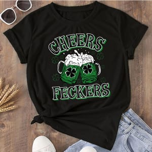 Black t-shirt featuring two green beer mugs with shamrocks, frothy beer spilling over, and the text \“CHEERS FECKERS\“ in bold, festive green and white lettering.