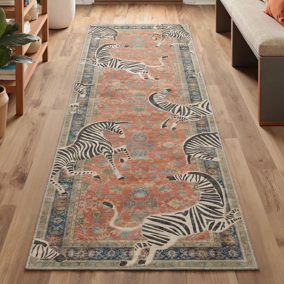 A runner rug with an ornate design in orange and blue features playful zebra motifs on a wooden floor beside a bench and plants.