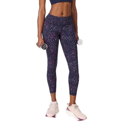 A person wearing patterned leggings and light sneakers holds two small dumbbells.