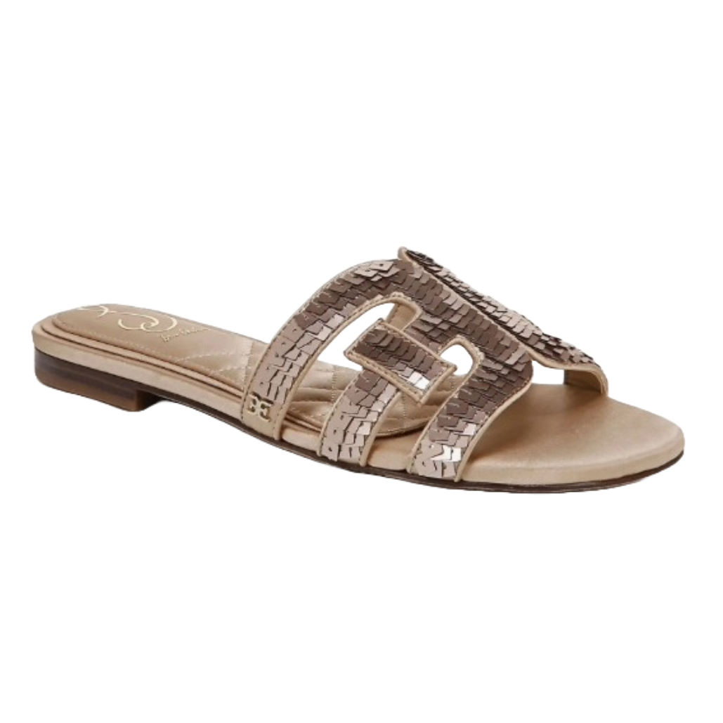 Sam Edelman sequined slides feature an open-toe design with a strap embellished with sequins in a geometric pattern, set on a low heel. The neutral color offers versatile styling options.