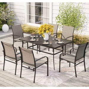 A 7-piece patio dining set includes a rectangular black metal table and six beige sling-back chairs. The table is set with plates and glasses, and a white vase with yellow flowers sits in the center on a light-toned outdoor rug.