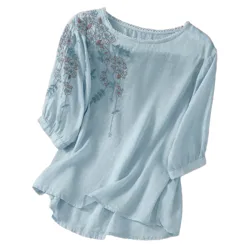 Light blue blouse with three-quarter sleeves, featuring floral embroidery on the left shoulder and sleeve.