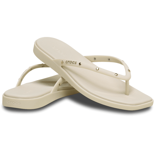 Pair of beige Crocs flip-flops with decorative studs and a simple strap design.