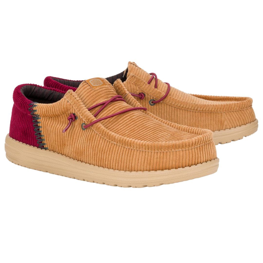 Hey Dude Wally Funk Corduroy Shoes feature corduroy material in a tan color with red accents. They have a casual moccasin-style design, lightweight sole, and maroon laces.