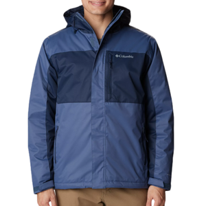 A man is wearing a Columbia Tipton Peak Insulated Jacket, which is color-blocked with navy and light blue, features a hood, and displays the brand's logo on the chest.