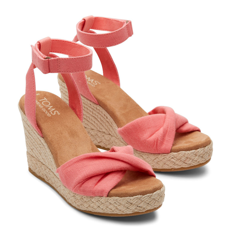 Coral pink wedge sandals with ankle straps, featuring a knotted fabric design on the front and woven espadrille-style platform heels.